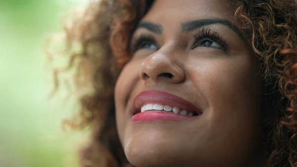 Joyful Latina woman opening eyes to sky smiling