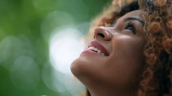 Happy Brazilian woman worshipping God looking up at sky smiling