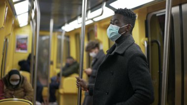 Metroda duran Afrikalı adam Coronavirus maskesi takıyor.