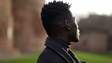 African young black man standing at park looking up in contemplation