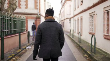 Şehrin dışında yürüyen Afrikalı bir adamın arkası. Avrupa kentinde Afrikalı kişi perspektifi