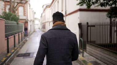 Şehrin dışında yürüyen Afrikalı bir adamın arkası. Avrupa kentinde Afrikalı kişi perspektifi