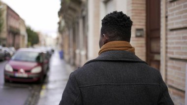 Şehir merkezindeki kaldırımda yürüyen Afrikalı bir adamın arkası. Afrikalı kişi bakış açısı
