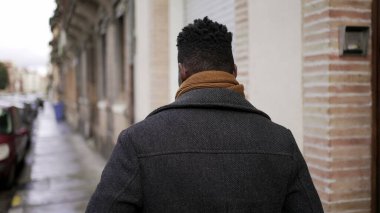 Şehir merkezindeki kaldırımda yürüyen Afrikalı bir adamın arkası. Afrikalı kişi bakış açısı