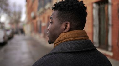 Şehir merkezindeki kaldırımda yürüyen Afrikalı bir adamın arkası. Afrikalı kişi bakış açısı