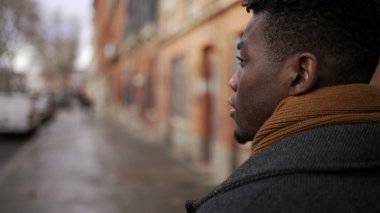 Şehir merkezindeki kaldırımda yürüyen Afrikalı bir adamın arkası. Afrikalı kişi bakış açısı