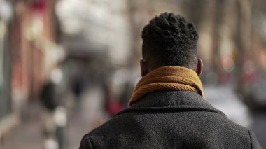 Siyahi bir adam şehrin dışında yürüyor.