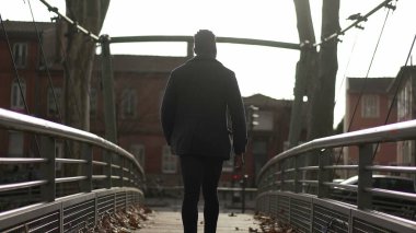 Back of person walking on top of bridge outside
