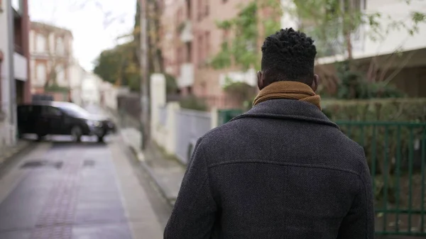 stock image Back of African man walking outside in city sidewalk downtown. African person perspective