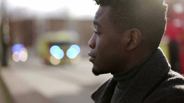 Anxious young black man suffering emotional pain sitting on sidewalk in street