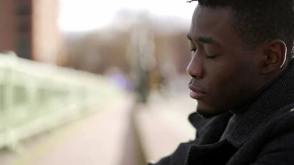 Anxious young black man suffering emotional pain sitting on sidewalk in street2