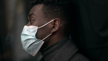 Black man commuter inside subway metro looking out window wearing covid-19 face mask