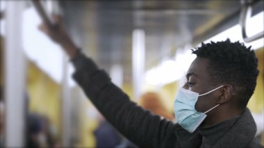 Metroda salgın sırasında siyah bir adam Covid-19 yüz maskesi takıyor.