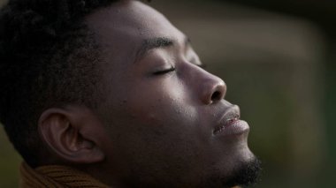 Siyah adam derin bir nefes alıyor gözlerini kapıyor ve meditasyon yapıyor.