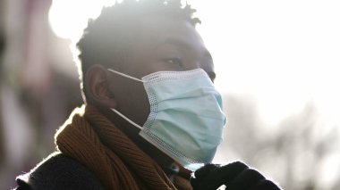 Siyahi adam cerrahi maskesini çıkarıyor, salgın konseptinin sonunda rahatlama ve temiz hava hissediyor.