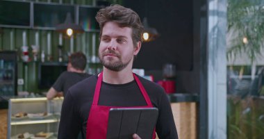 Genç girişimci kafede duran tablet kontrol cihazını kontrol ediyor. Çevrimiçi sipariş envanterine bakan kişi