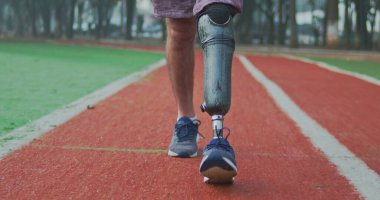 Koşu yolunda yürüyen protez bacaklı engelli bir sporcunun arka planı