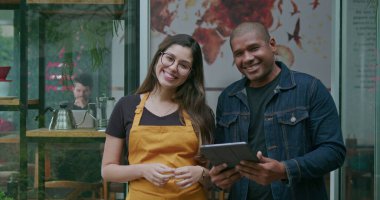 Küçük işletme tabletinde çalışan Afro-Amerikalı bir yönetici kahve dükkanının girişinde bayan çalışanla konuşuyor. Kafe restoranının iki farklı mutlu çalışanının portresi.