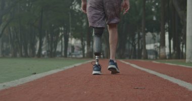 Koşu yolunda yürüyen protez bacaklı engelli bir sporcunun arka planı