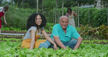 Dışarda çiftçilik yapan iki farklı insanın portresi kameraya gülümseyen arka planda çalışan işçilerle organik gıda yetiştiren tarım araçları kullanan. Mutlu Güney Amerika halk bahçıvanları