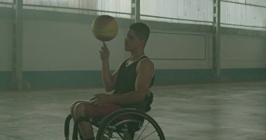 İki belden aşağısı felçli sporcu dışarıda basketbol oynuyor ve takım arkadaşına pas veriyor. Özürlü olarak azim ve spor