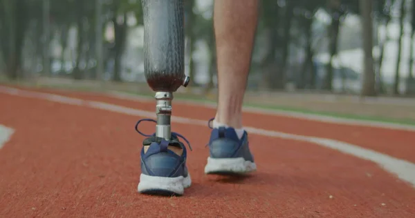 One disabled athlete walks outdoors with prosthetic leg. Male person with disability