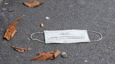 Yüzünde cerrahi maske var. Covid salgını döneminde atık kirliliği. El bilgisayarı görüntüleri