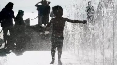 Su parkı jetlerinde koşan bulanık küçük çocuk. Çocuk ferahlatıcı suda sıcak yaz gününde eğleniyor.