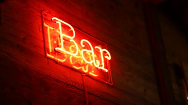 İşletme girişinde kırmızı renkli bar floresan ışığı ve ahşap yüzey reklam işi el hareketinde.