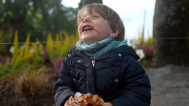 Sokak yemeği yerken gülen mutlu çocuk. Güzel, küçük, otantik çocuk. Gerçek hayatta gül ve gülümse.