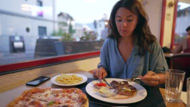 Restoranda biftek yiyen bir kadın. Yemek sırasında tabakta sığır eti kesen kişi