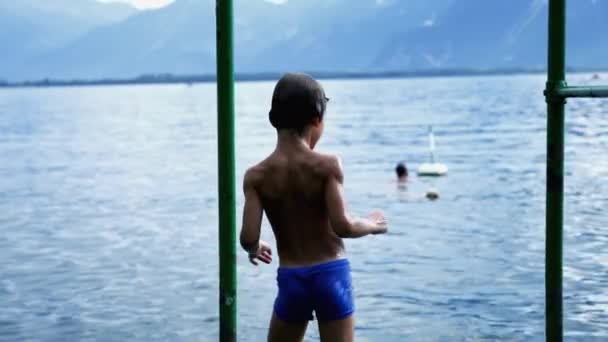 Спине Маленького Мальчика Стоящего Пирсе Видом Озерную Воду Влажный Ребенок — стоковое видео