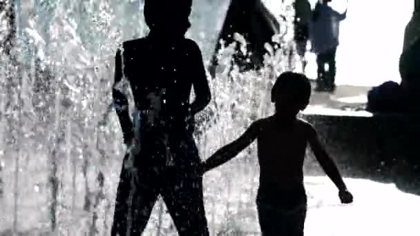 暑い夏に都会のウォーターパークシティで遊ぶ子供たちのシルエット — ストック動画