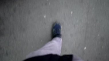 Şehrin göbeğinde yürüyen insan bacakları. Kaldırımda yürüyen ayaklara bakan insanların bakış açısı