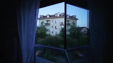 Gün batımının alacakaranlık saatinde pencere camları yansıyor. Akşamları Avrupa binasının mavi huysuz tonu