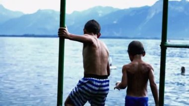 İskelede dikilen iki küçük çocuğun arkasında. Çocuk göle dalıyor. Islak Çocuk yaz tatilinin tadını çıkarıyor. Çocuk düşüşü