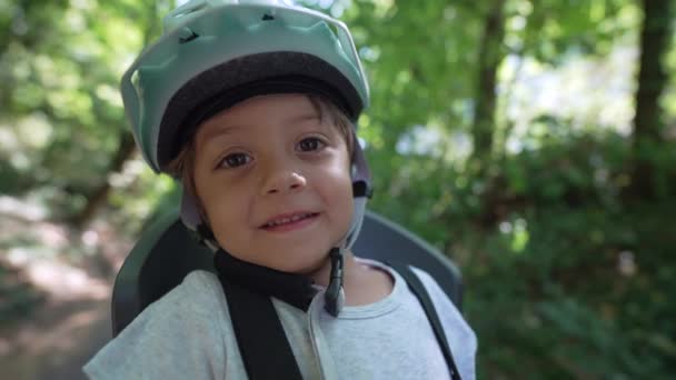 小男孩戴着防护头盔 对着摄像机微笑 小孩坐在自行车座位上 面目全非儿童安全和保护概念 — 图库视频影像