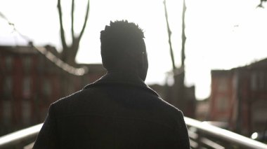 Kararlı genç siyah adam şehir köprüsünde yürüyor.