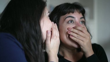 Friends sharing gossip whispering secret to woman ear telling SHOCKING news revelation. Two women sharing information