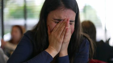 Young woman laughing covering face in laughter. Girl holding laugh covers face feeling happy