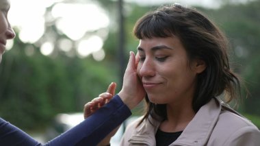 Two friends hugging each other standing outside with EMPATHY and SUPPORT. Friendship concept of female friend EMBRACING suffering person