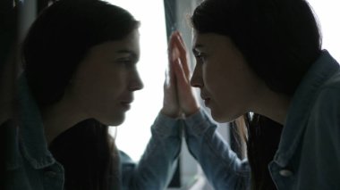 Anxious woman looking at her own reflection at bathroom mirror feeling regret and preoccupation