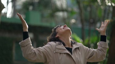 Religious thankful young woman raising arms in air celebrating life in prayer to God. Spiritual person feeling HOPE and FAITH feeling FREE