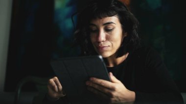 South American woman holding tablet device looking at content online