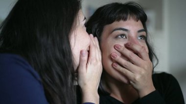 Friends sharing gossip whispering secret to woman ear telling SHOCKING news revelation. Two women sharing information