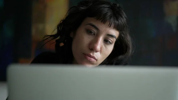 One pensive hispanic woman in front of laptop. A thoughtful latin person using computer thinking of an idea