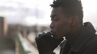 Şık tefekkür eden Afrikalı adam ufka bakıyor kışlık kıyafetler giyiyor.