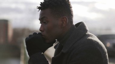 Şık tefekkür eden Afrikalı adam ufka bakıyor kışlık kıyafetler giyiyor.