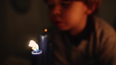 Mum ışığını üfleyen çocuğun bulanık görüntüsü. Küçük bir çocuk mum ışığını yavaş çekimde üflüyor. Dilek tutma konsepti