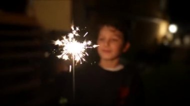 Bir genç gece maytap tutuyor. Mutlu çocuk tatilleri kutluyor